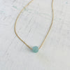 The Jenny Blues Amazonite Necklace by ZEN by Karen Moore by on white wood emphasizing the gemstone