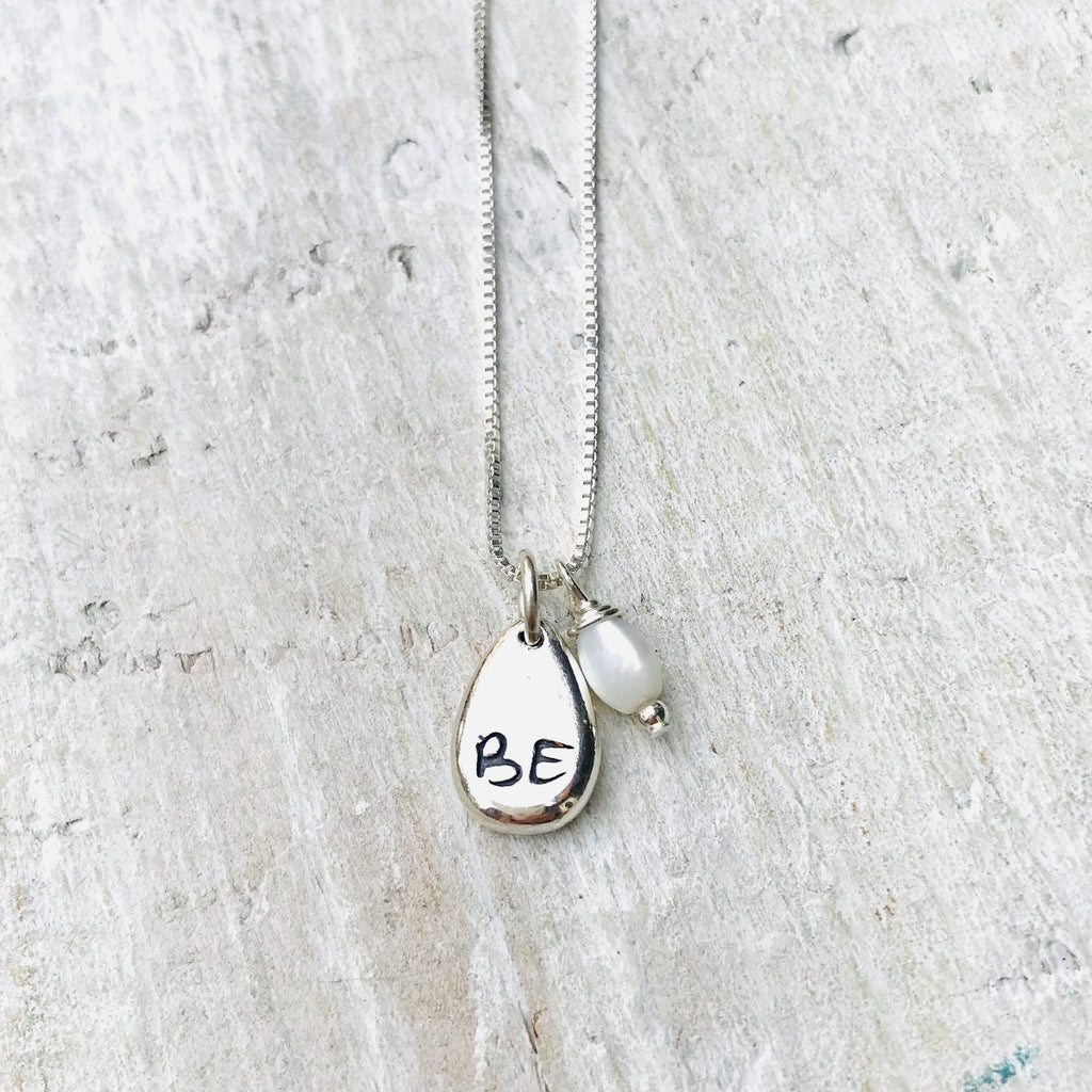 Just BE Nutured Charm Necklace by ZEN by Karen Moore Jewelry close up of charms on white wood