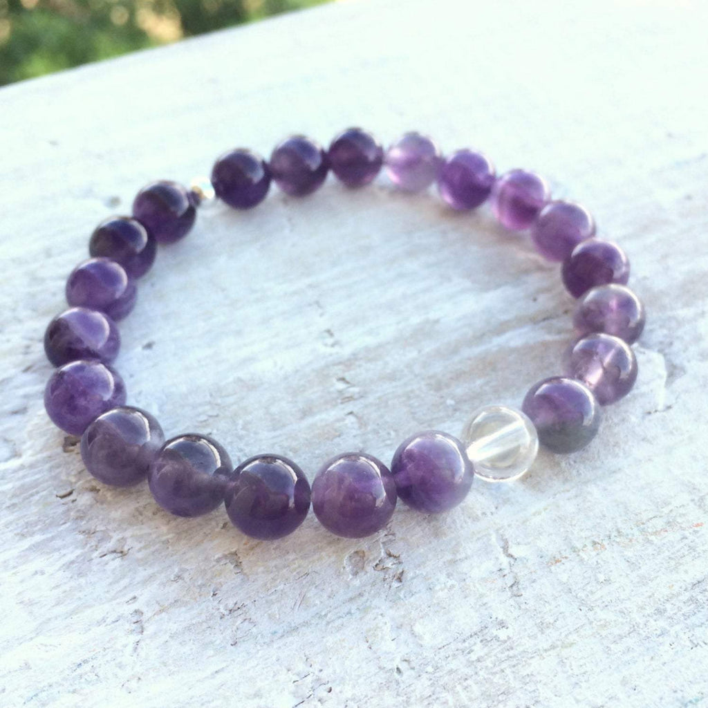 Amethyst & clear crystal quartz Clear Your Mind Bracelet by ZEN by Karen Moore overhead view on white wood