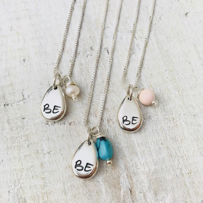 Just BE Love Charm Necklace by ZEN by Karen Moore Jewelry close up of charms on white wood