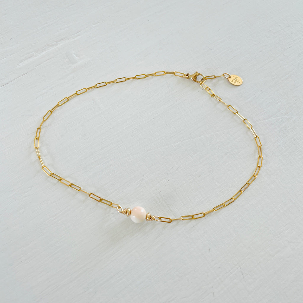 ZEN by Karen Moore Anchored in Clarity Conch Shell Anklet 14kt gold filled paperclip chain on white wood background