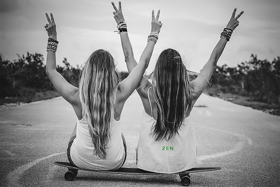 two girls sitting on a skateboard with their backs to the camera