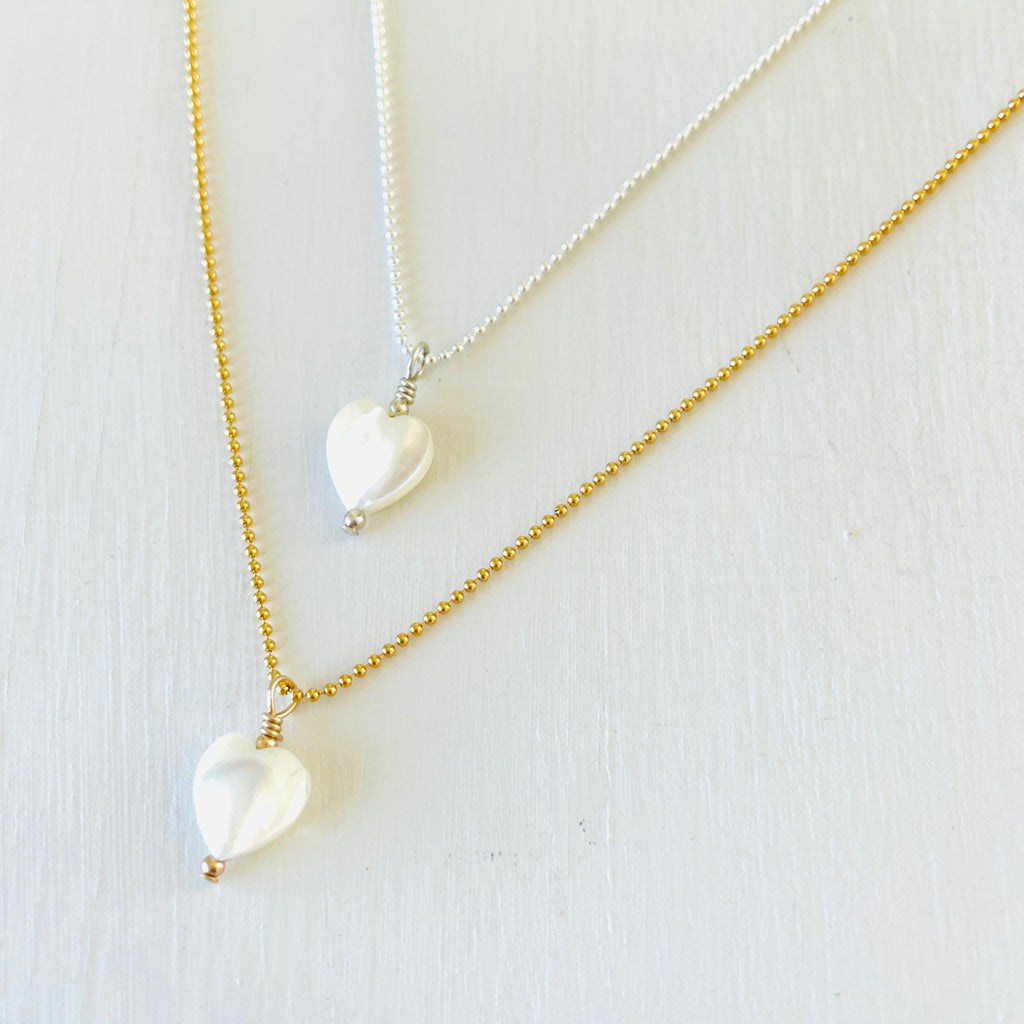 Mother of Pearl gemstone charm necklace with silver and gold chains on a white background