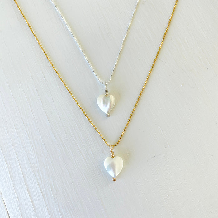 Mother of Pearl gemstone charm necklace with silver and gold chains on a white background
