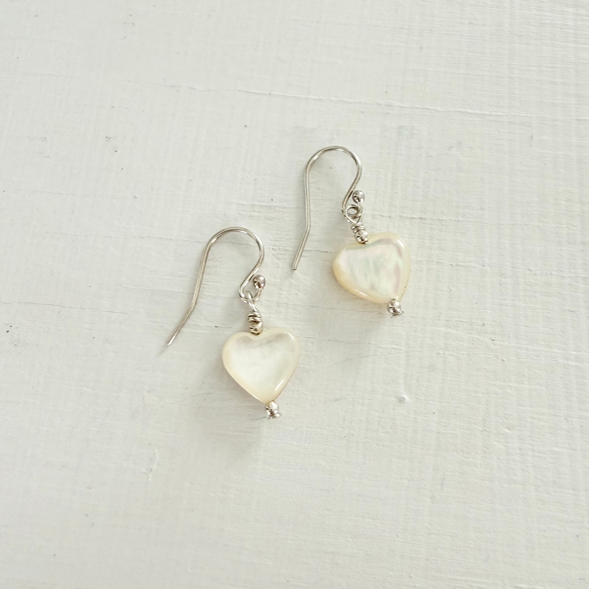 Heart-shaped earrings on a light fabric background