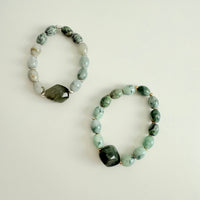 Two beaded bracelets with green and gray stones on a light background