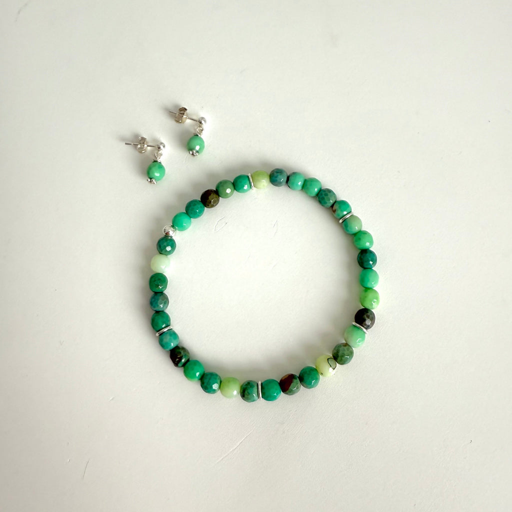 Green beaded bracelet and earrings on a white background