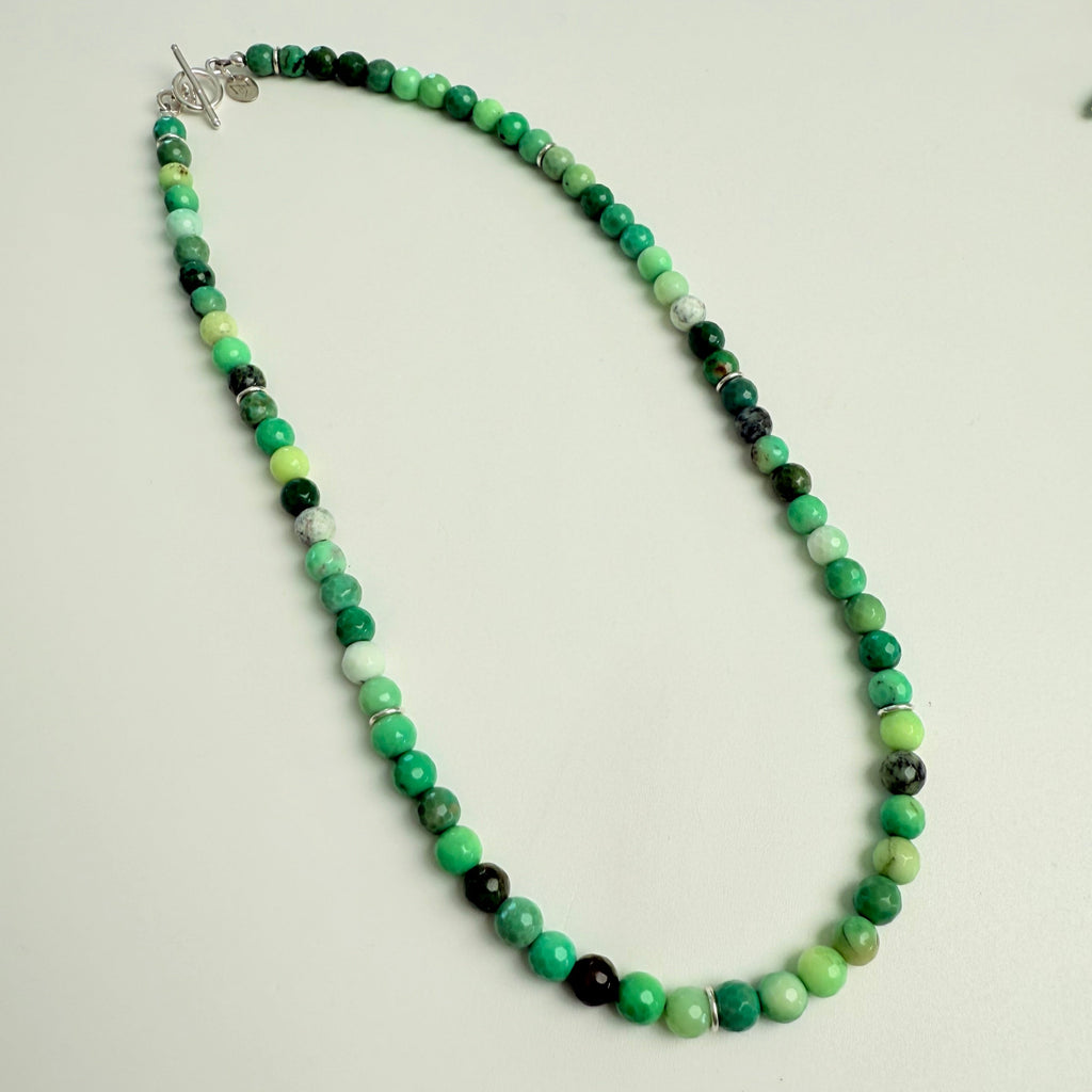 Green beaded necklace with a silver clasp on a light gray background