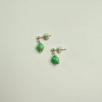 Pair of earrings with green beads on a light gray background