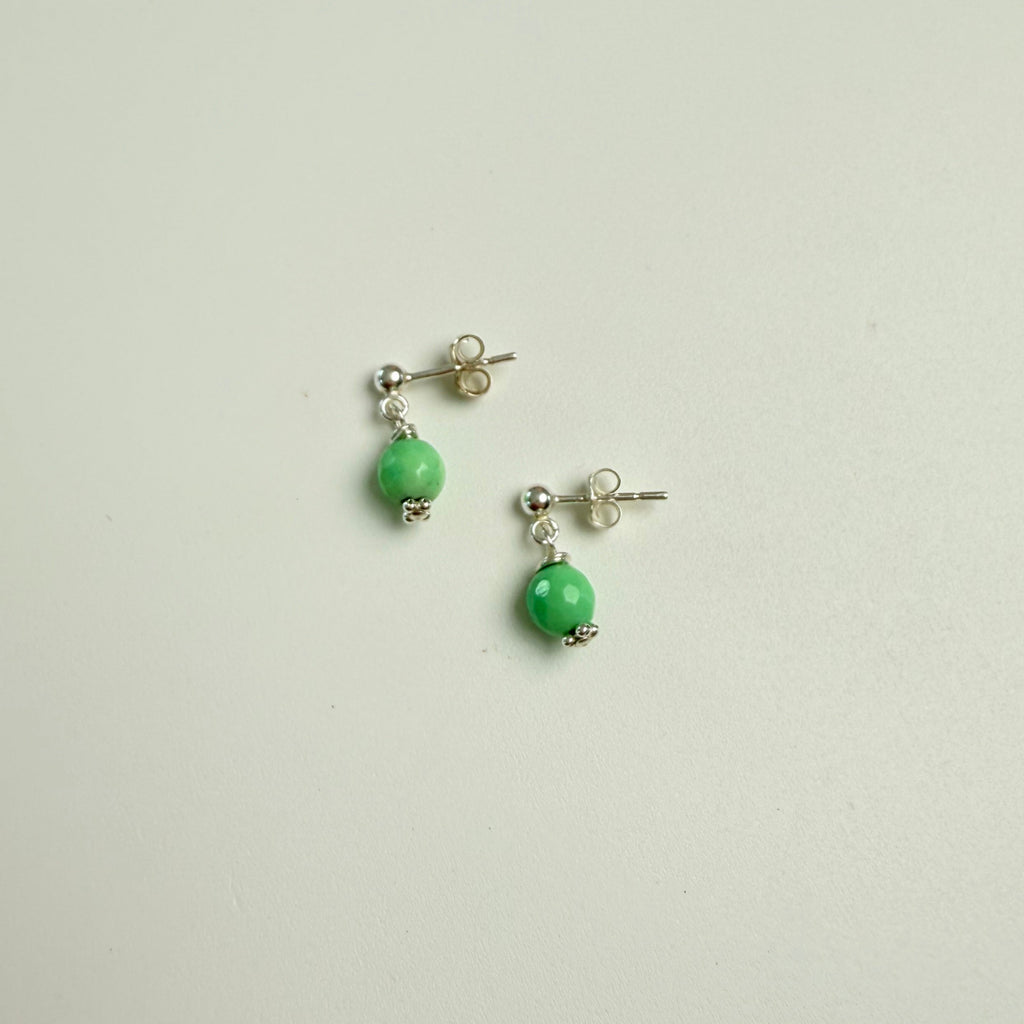 Pair of earrings with green beads on a light gray background