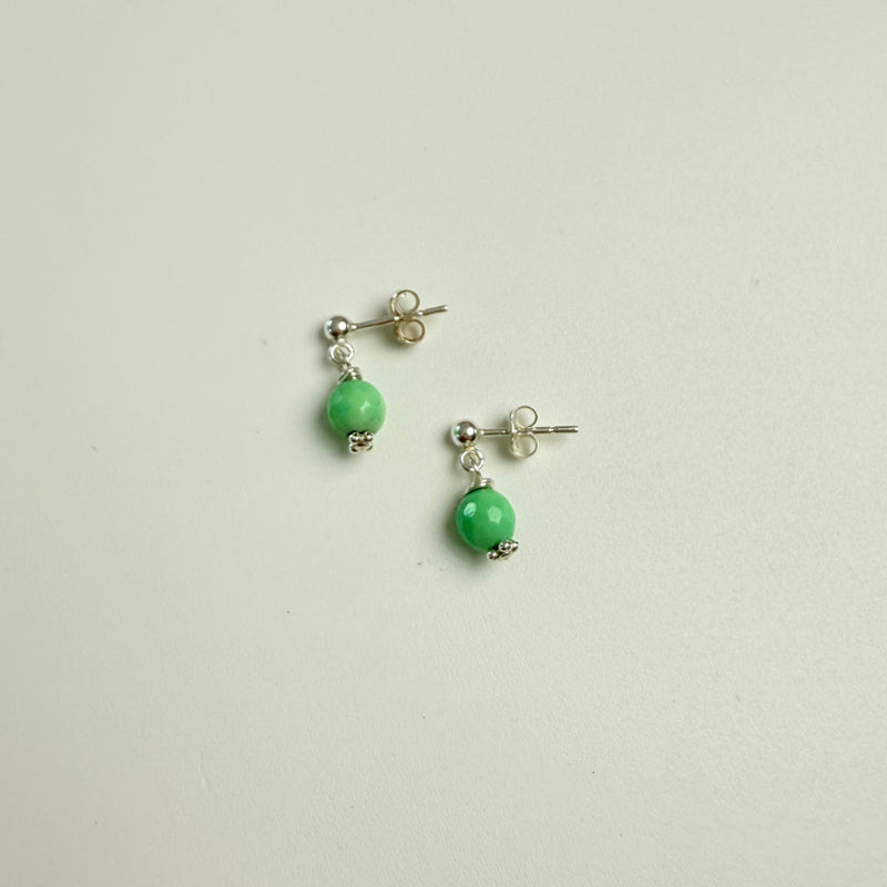 Pair of earrings with green beads on a light gray background