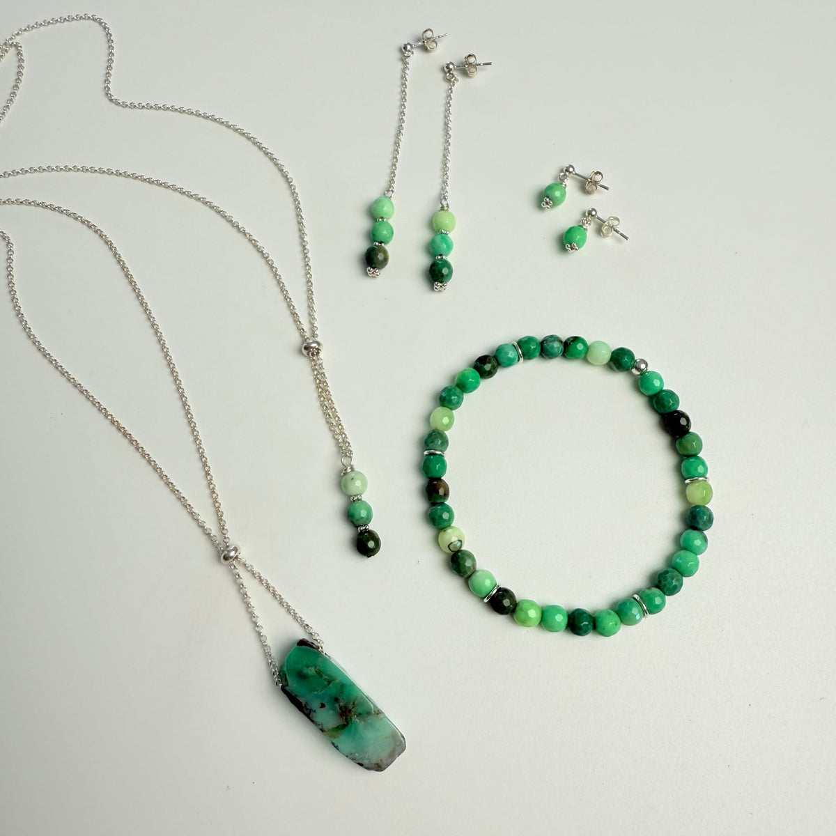 Jewelry set with necklace, bracelet, and earrings on a light gray background