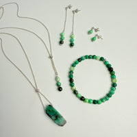 Jewelry set with necklace, bracelet, and earrings on a light gray background