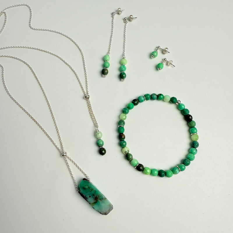 Jewelry set with necklace, bracelet, and earrings on a light gray background