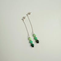 Beaded bracelet with green and black beads on a light gray background