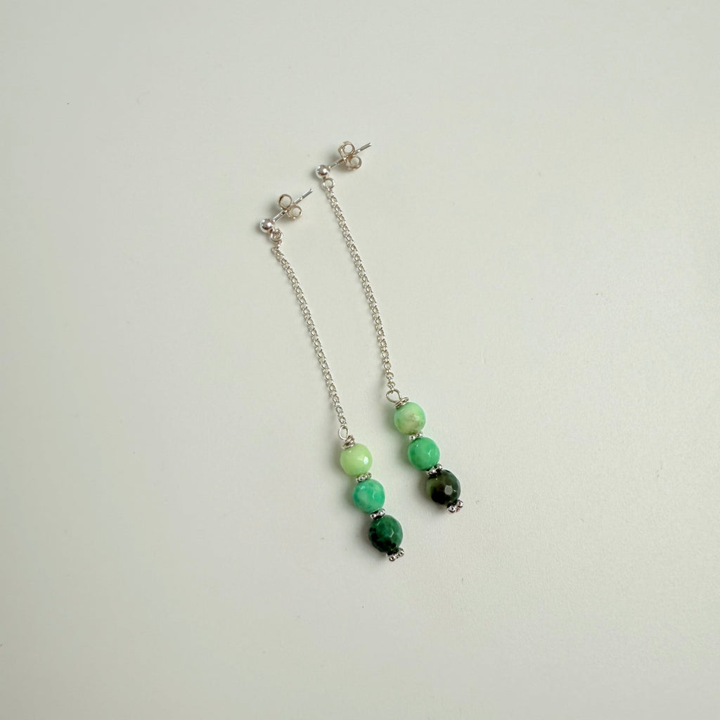 Beaded bracelet with green and black beads on a light gray background