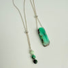 Necklace with a green pendant and beads on a white background