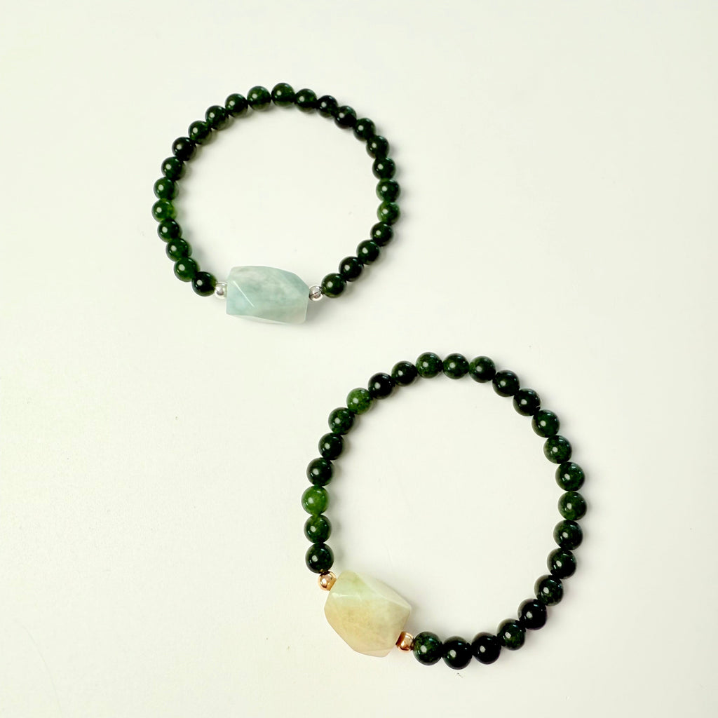 Two beaded bracelets with green and white stones on a beige background