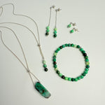 Set of green and black beaded jewelry on a light gray background