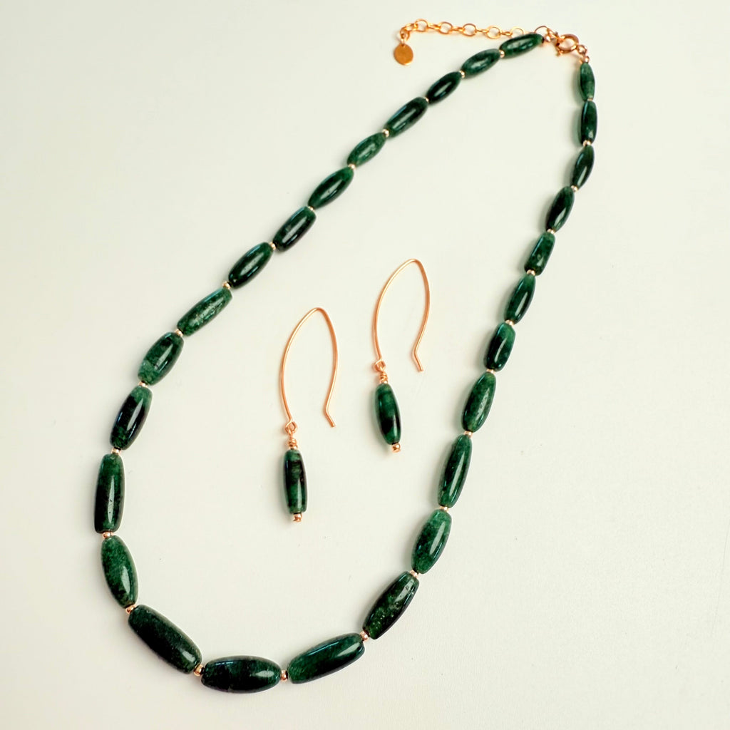 Green beaded necklace and earrings on a light background