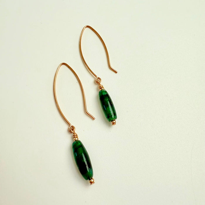 Pair of green beaded earrings on a light beige background