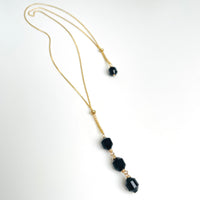 gold long Necklace with black beads on a white background