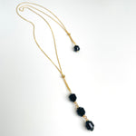 gold long Necklace with black beads on a white background