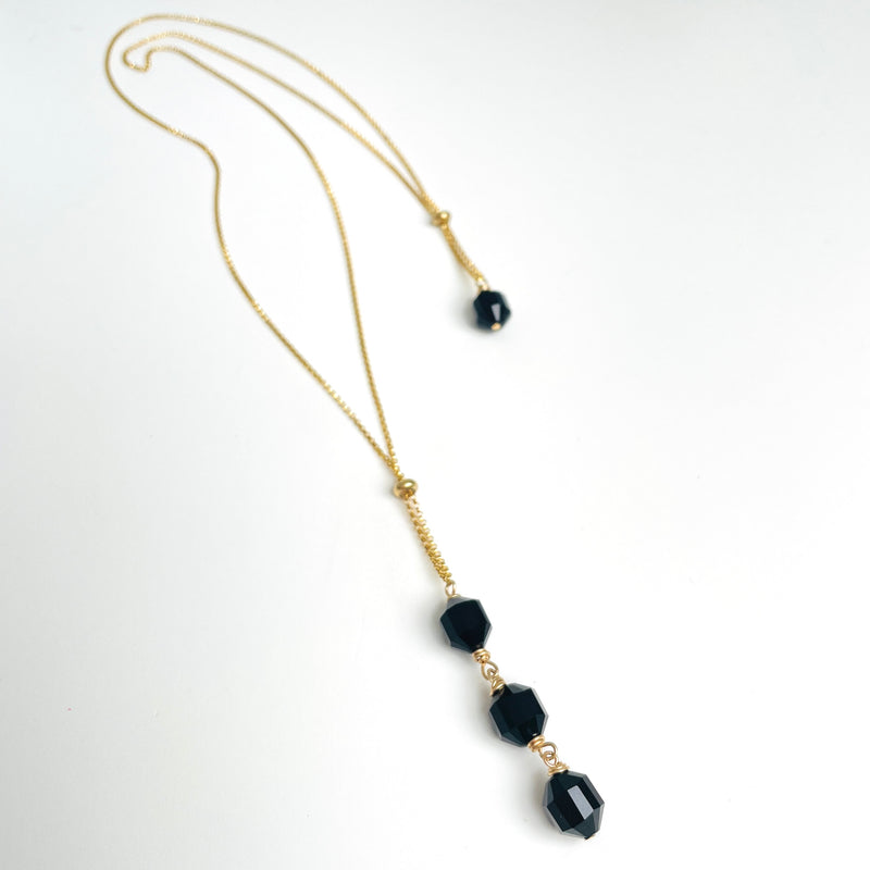 gold long Necklace with black beads on a white background