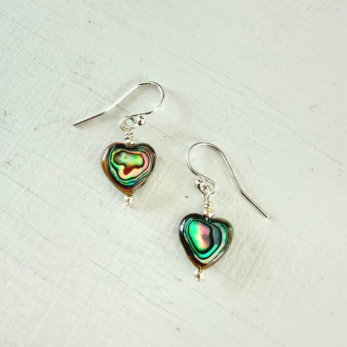 Heart-shaped abalone shell earrings on a light background