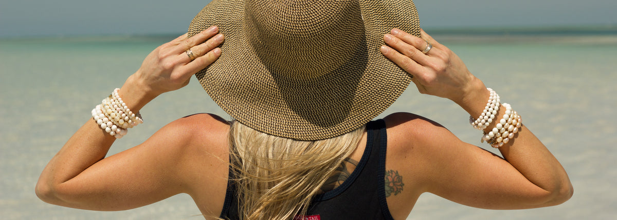 woman holding her hat wearing ZEN by Karen Moore conch shell jewelry
