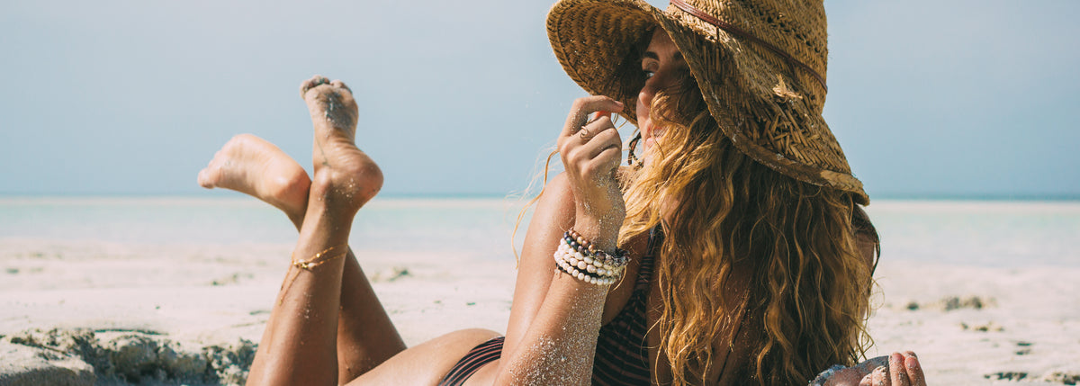 woman laying on the beach wearing ZEN by Karen Moore jewelry