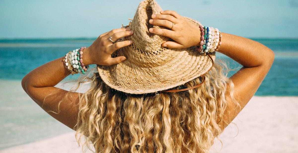 Woman holding a hat wearing ZEN by Karen Moore handmade jewelry