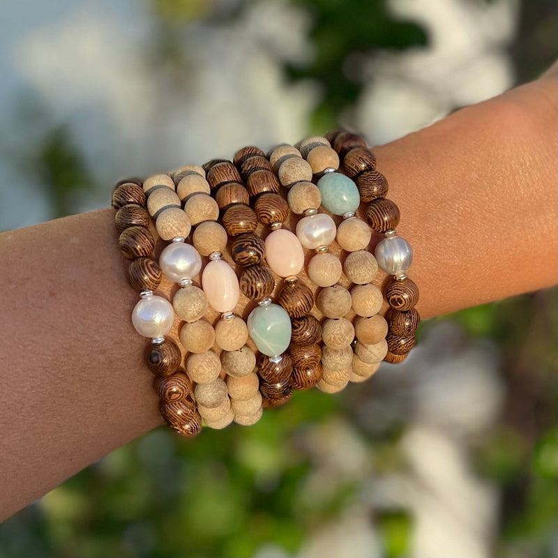 Mojo Tiger Wood & Sandalwood Bracelets by ZEN by Karen Moore layered on an arm in the sunshine
