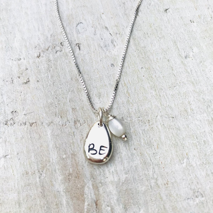 Just BE Nutured Charm Necklace by ZEN by Karen Moore Jewelry close up of charms on white wood