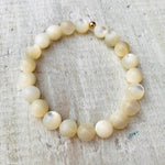 Be Nurtured Mother-of-Pearl Bracelet by ZEN by Karen Moore with gold accent bead on white wood