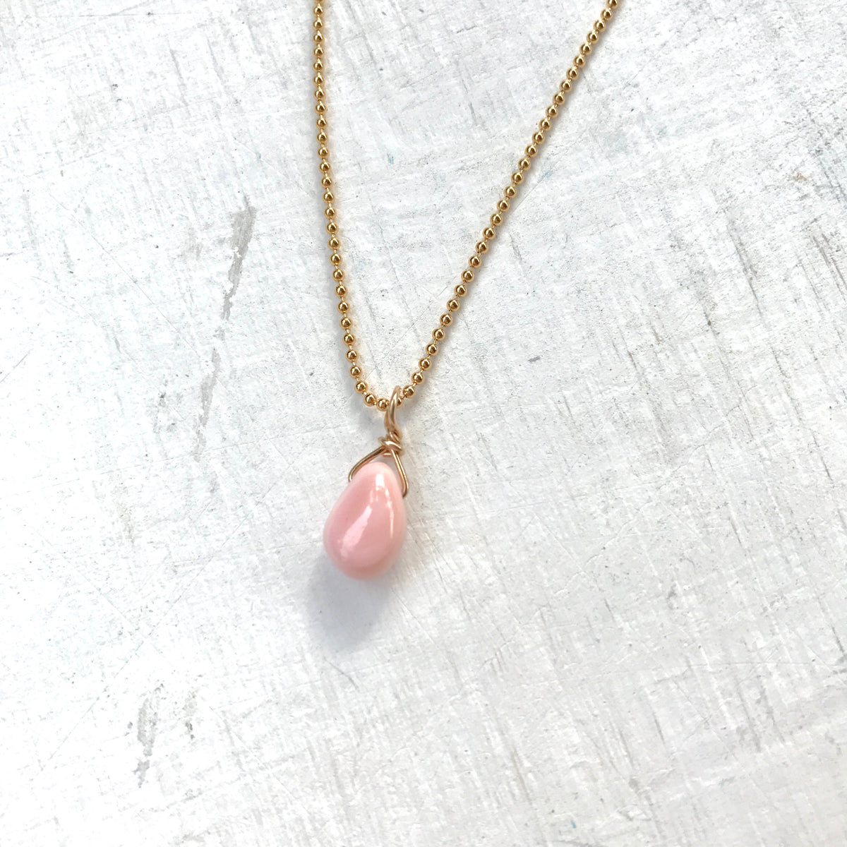 Delicate Inspiration conch shell necklace in 14K gold by ZEN Karen Moore on white wood