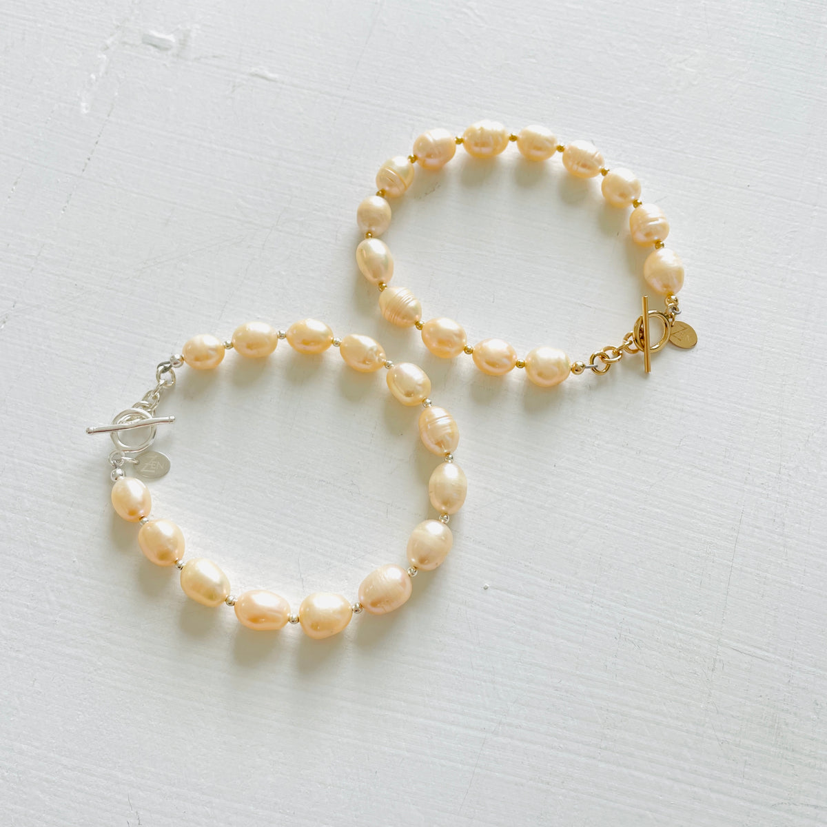 Just Peachy Pearl Bracelets, one with sterling silver clasp and one with 14K gold clasp by ZEN by Karen Moore Jewelry on white background