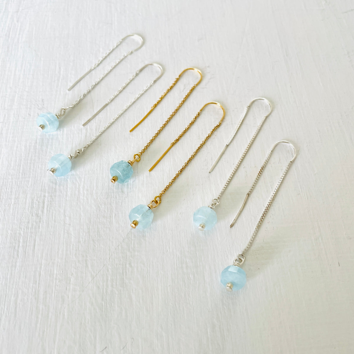 Drop into the Calm Aquamarine Earrings by ZEN by Karen Moore jewelry showing two pairs in sterling silver with a pair in 14K gold in the middle angled view on white background