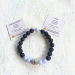 Blue lace agate & lava stone I Am Calm Aromatherapy Bracelet by ZEN by Karen Moore with gemstone-meaning cards on white wood