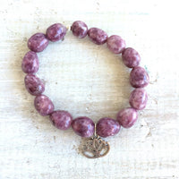 Let Go & Transform Lepidolite Bracelet by ZEN by Karen Moore overhead view of lotus charm on white wood