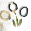 Rainbow obsidian & turquoise Rock of Turquoise Aromatherapy Bracelet by ZEN by Karen Moore shown with two other gemstone bracelets with feathers on white wood