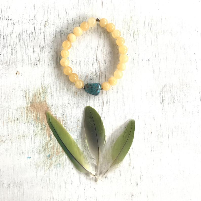 Calcite & turquoise Sunshine Turquoise Bracelet by ZEN by Karen Moore overhead view with feathers  on white wood