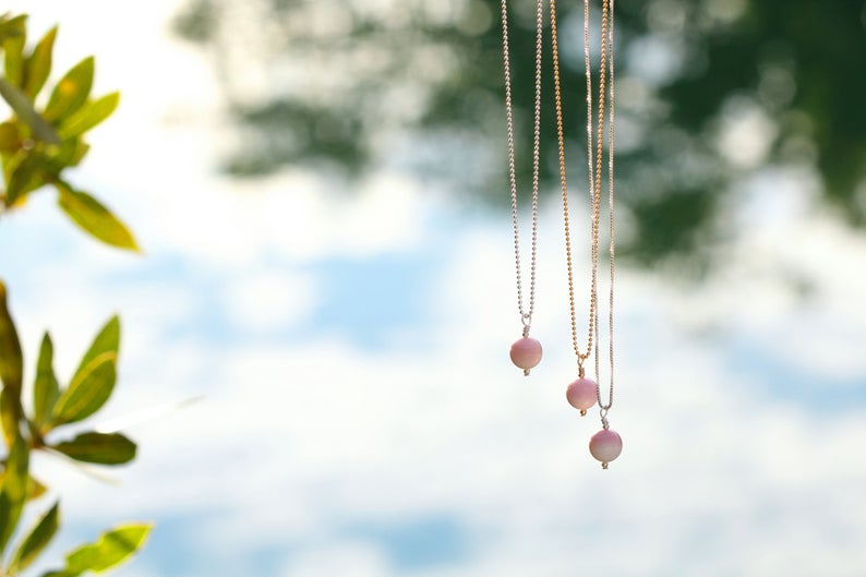 Three Simply Conch Shell Necklace with mini gem by ZEN by Karen Moore hanging outside with leaves and the sky in the background