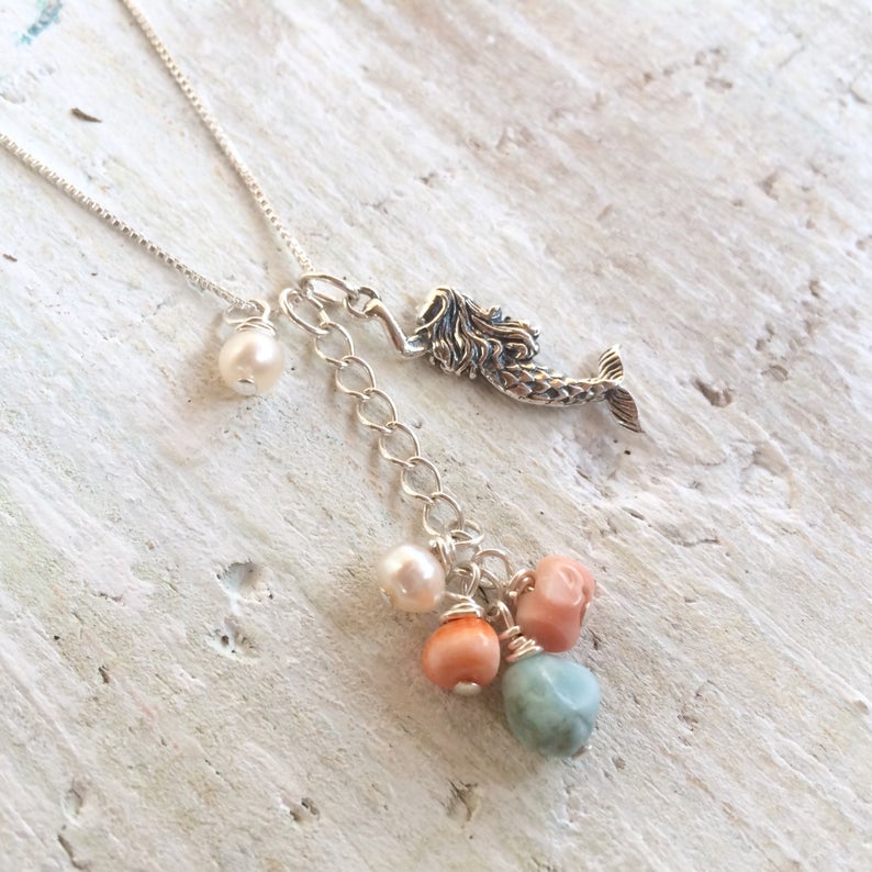 Mermaid Treasure Charm Necklace by ZEN by Karen Moore showing the three different charms angle view on white wood