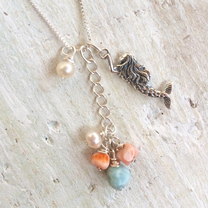 Mermaid Treasure Charm Necklace by ZEN by Karen Moore showing the three different charms viewed from above on white wood