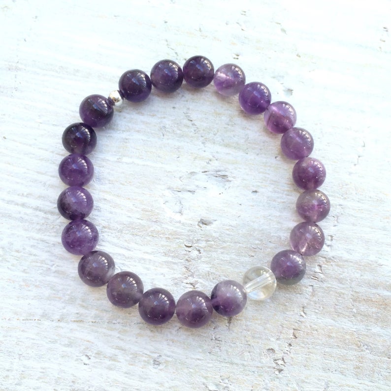 Amethyst & clear crystal quartz Clear Your Mind Bracelet by ZEN by Karen Moore overhead view on white wood