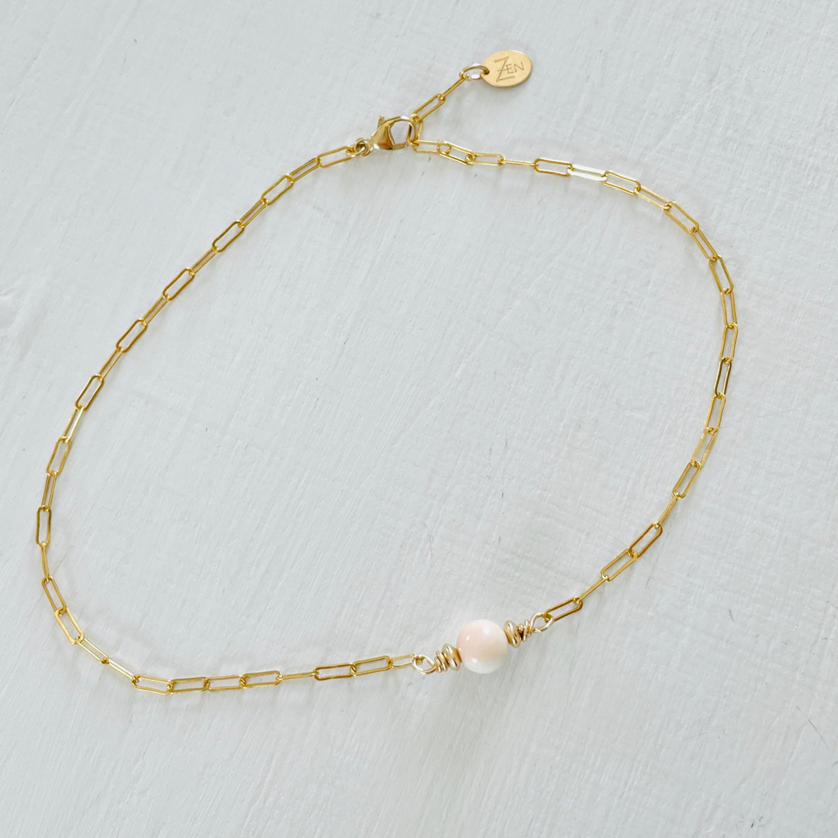ZEN by Karen Moore Anchored in Clarity Conch Shell Anklet 14kt gold filled paperclip chain on white wood background