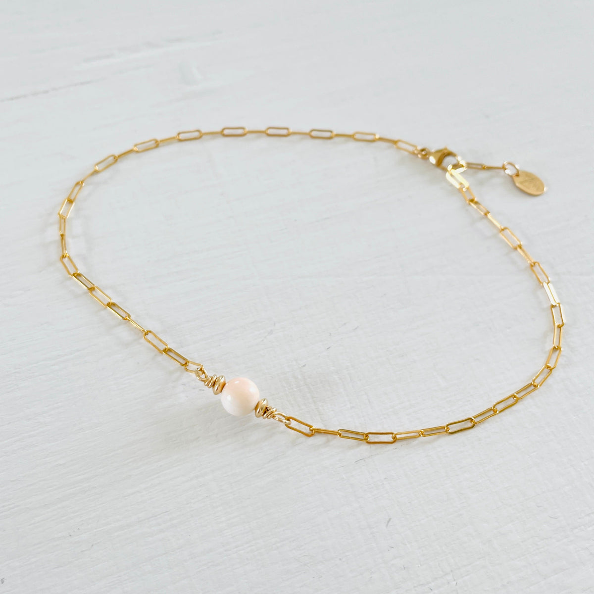 ZEN by Karen Moore Anchored in Clarity Conch Shell Anklet 14kt gold filled paperclip chain on white wood background